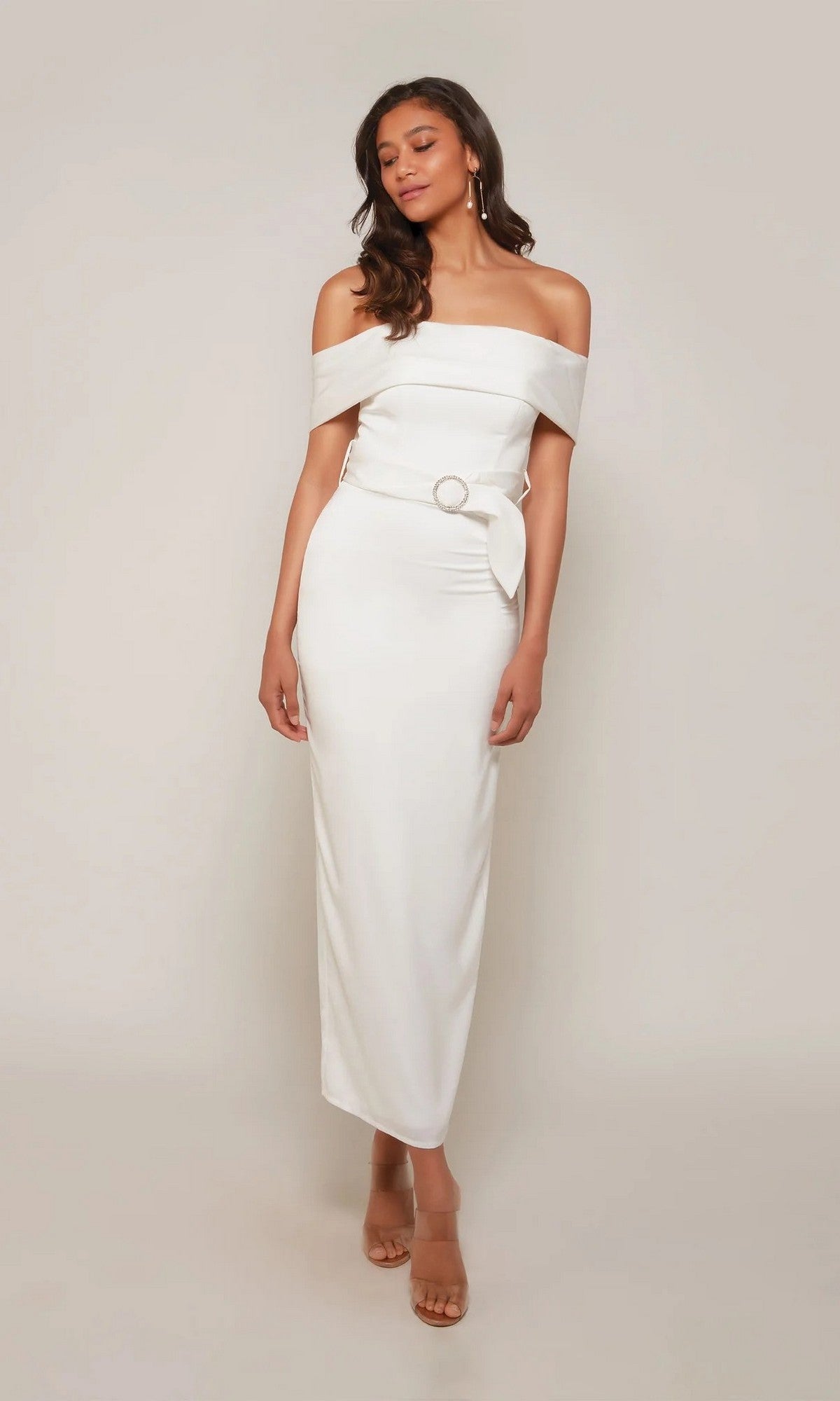 Woman wearing the Alyce 70041 tea length formal dress, featuring off-the-shoulder style with belt and buckle detail—ideal as a chic wedding guest outfit against a plain light background.